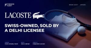 Lacoste brand audit by FashionAudit: Lacoste logo and the headline “Swiss-Owned, Sold by a Delhi Licensee” over a white piqué cotton polo shirt folded with a tennis racket and a tennis ball