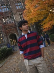 A man in a striped rugby shirt layered over an Oxford collar with baggy chinos