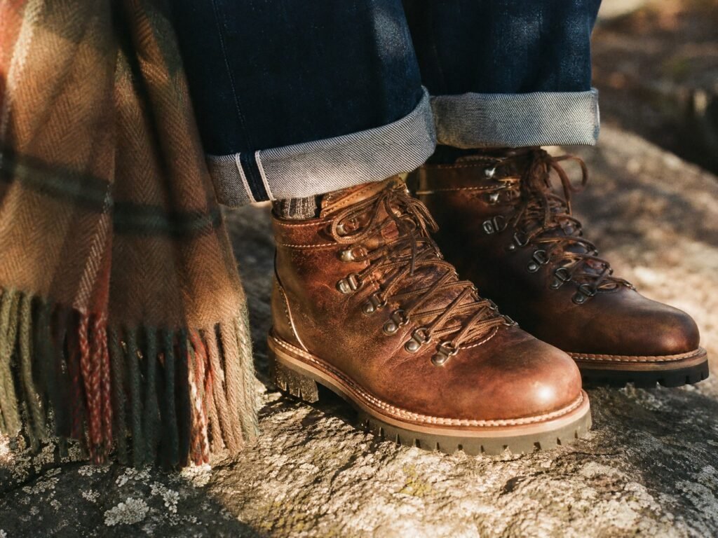 Brown leather hiking boots with raw denim turn-ups and a plaid wool scarf